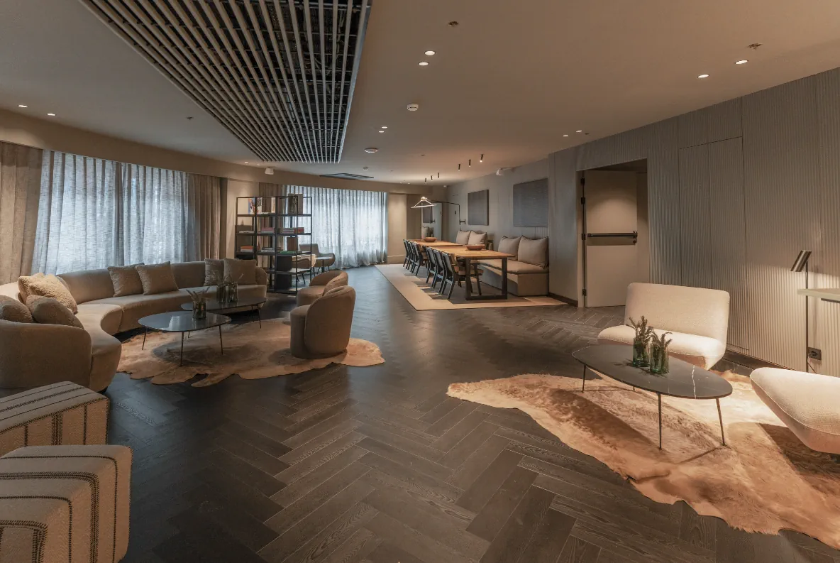 Saló de la primera planta de Casa Serras amb parquet en espiga, sofàs corbats i taula de menjador al fons.