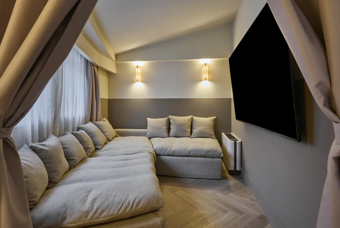 Racó d'estar d'una habitació familiar de Casa Serras amb sofà modular i apliques de paret, separat amb cortines.